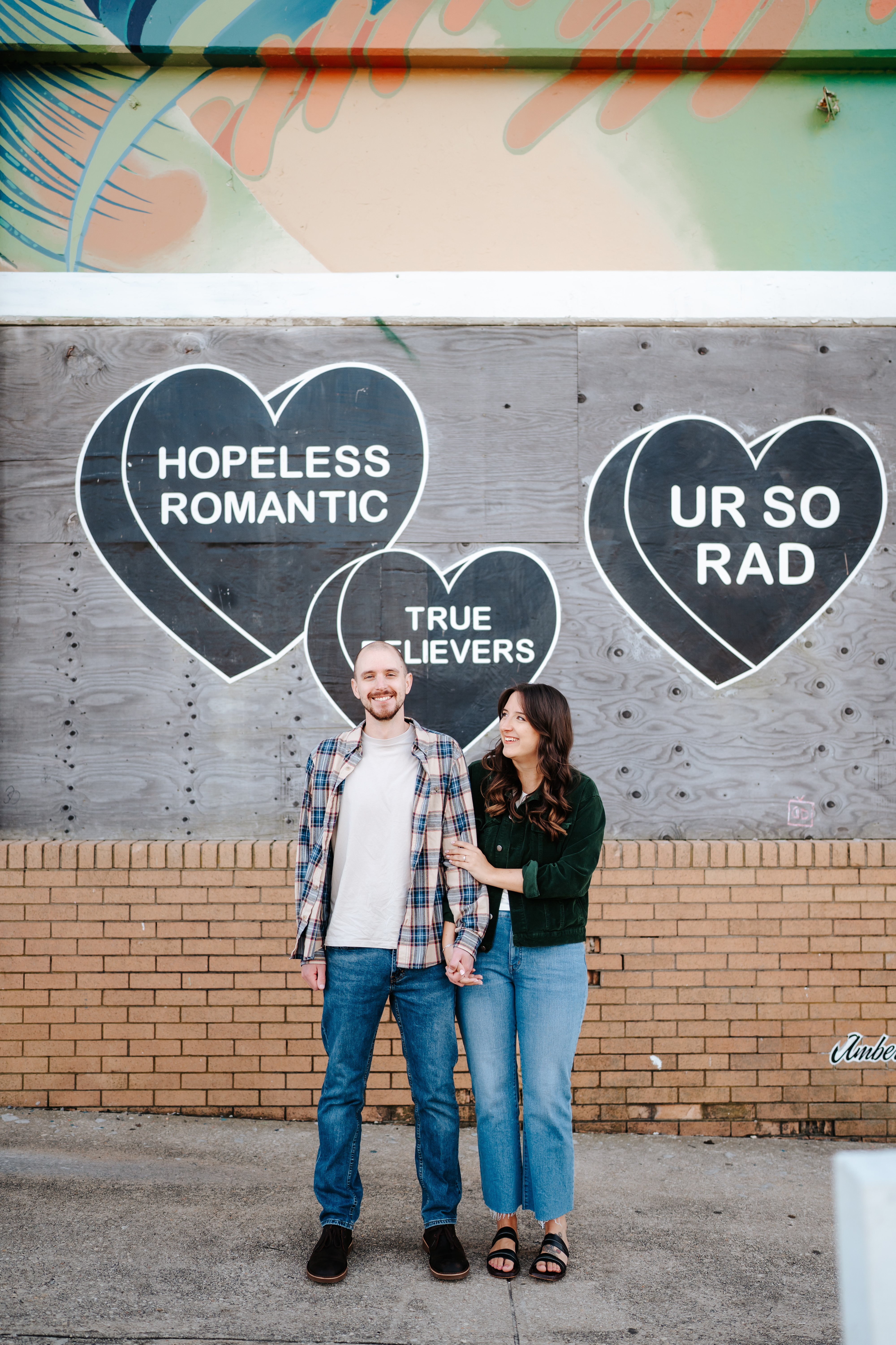 A couple at Asbury Park Beach during their engagement session with Maryland Wedding Photographer capturing the artistic mural backdrops