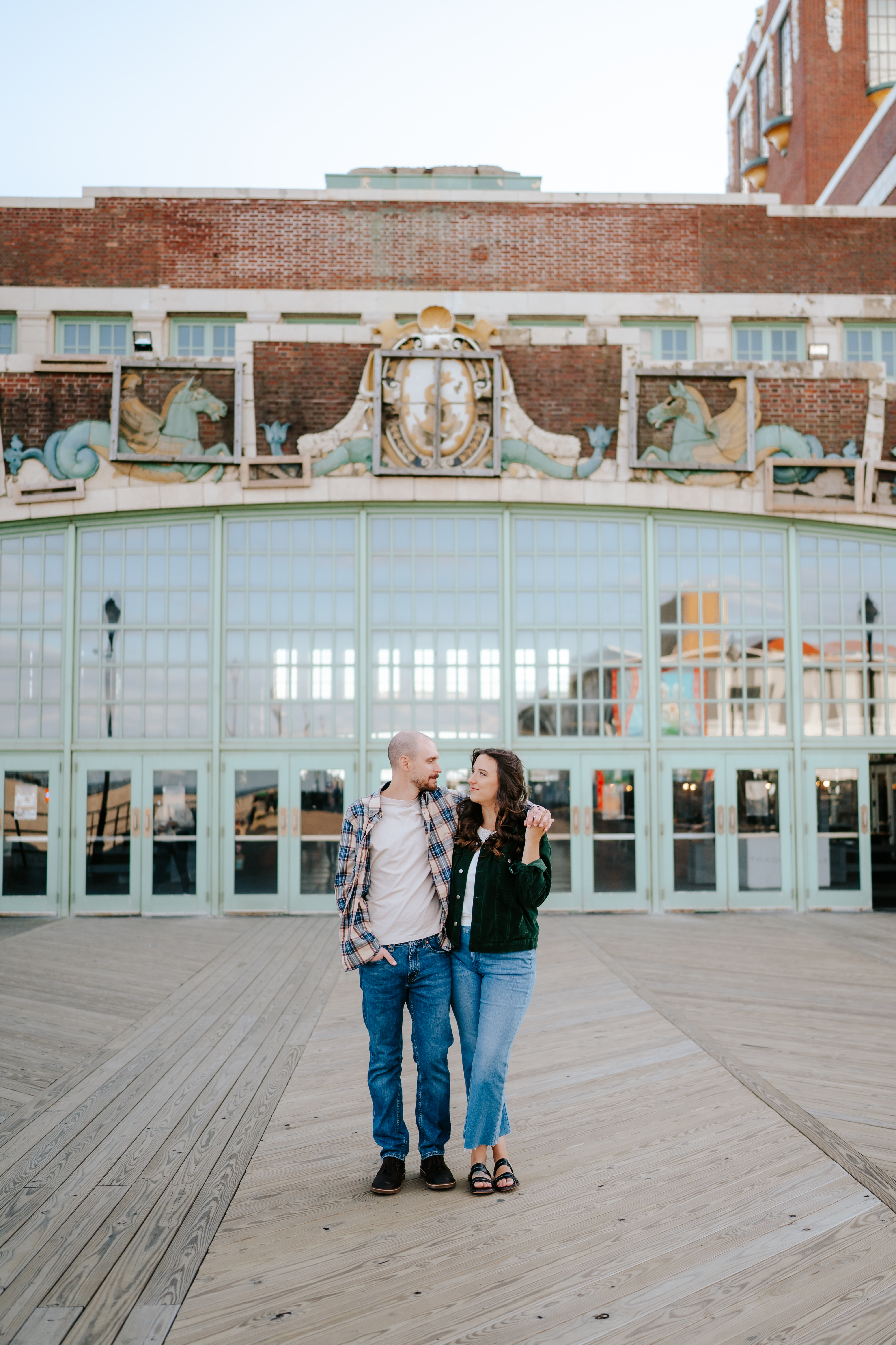 Joyful couple sharing a candid moment during their engagement photo shoot at Asbury Park Boardwalk, captured by Brenna Marie Photography, Maryland's true-to-color and candid storyteller for laid-back couples