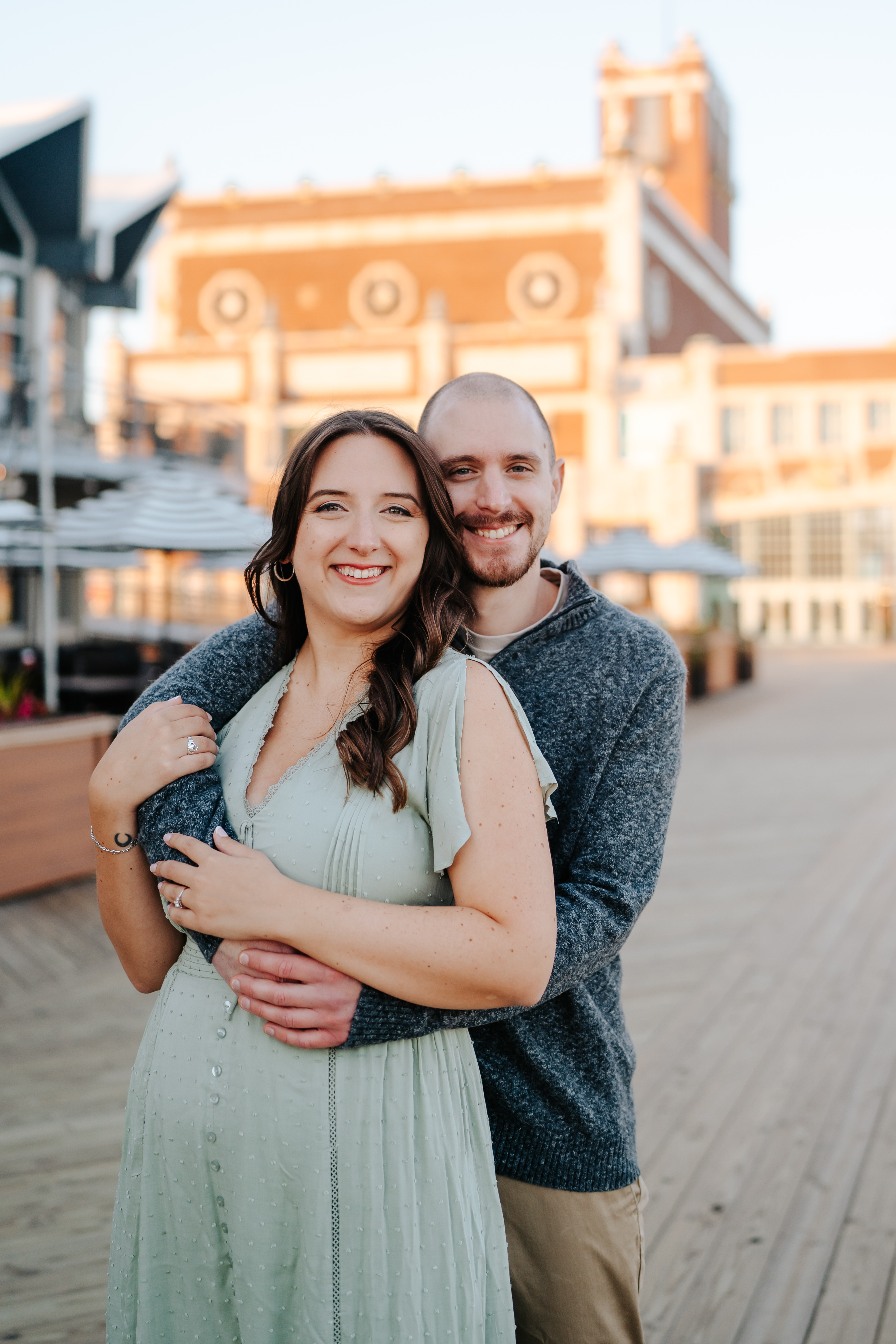 Couple embracing in a sun-kissed engagement photo on Asbury Park Boardwalk, captured by Maryland Wedding Photographer, showcasing candid love and joyful moments