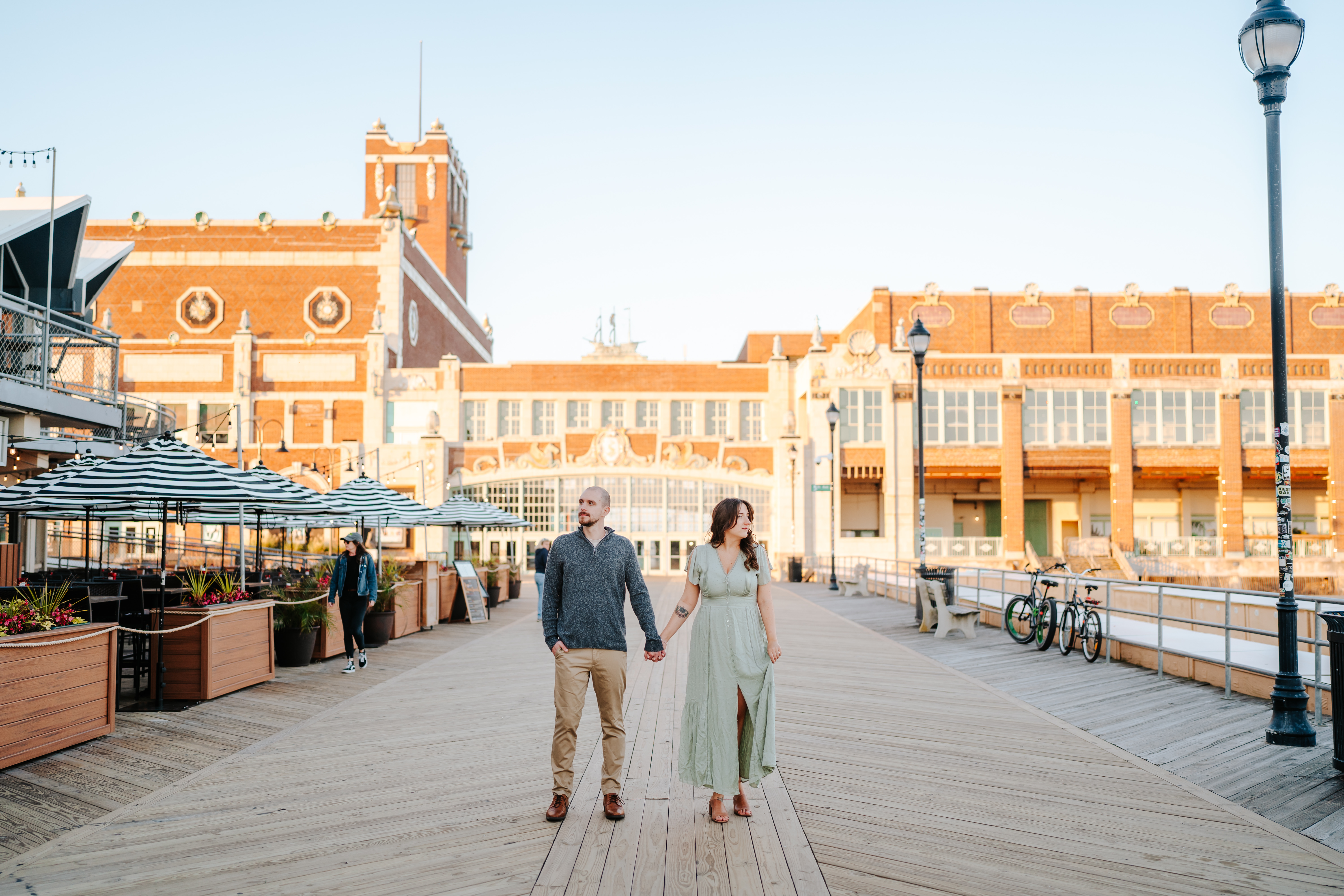 Couple embracing in a sun-kissed engagement phoCouple embracing in a sun-kissed engagement photo on Asbury Park Boardwalk, captured by Maryland Wedding Photographer, showcasing candid love and joyful momentsto on Asbury Park Boardwalk, captured by Maryland Wedding Photographer, showcasing candid love and joyful moments