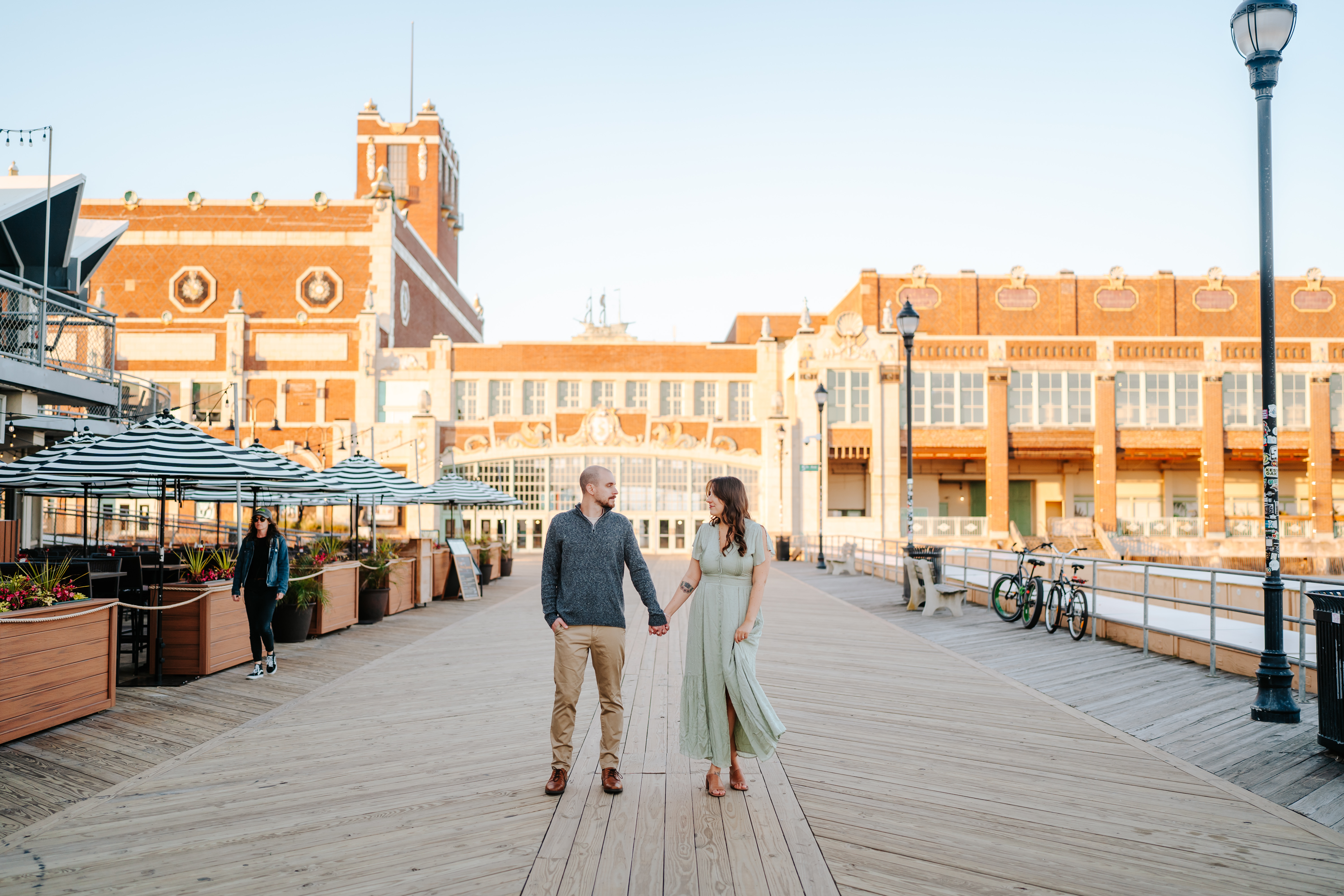 Couple embracing in a sun-kissed engagement photCouple embracing in a sun-kissed engagement photo on Asbury Park Boardwalk, captured by Maryland Wedding Photographer, showcasing candid love and joyful momentso on Asbury Park Boardwalk, captured by Maryland Wedding Photographer, showcasing candid love and joyful moments