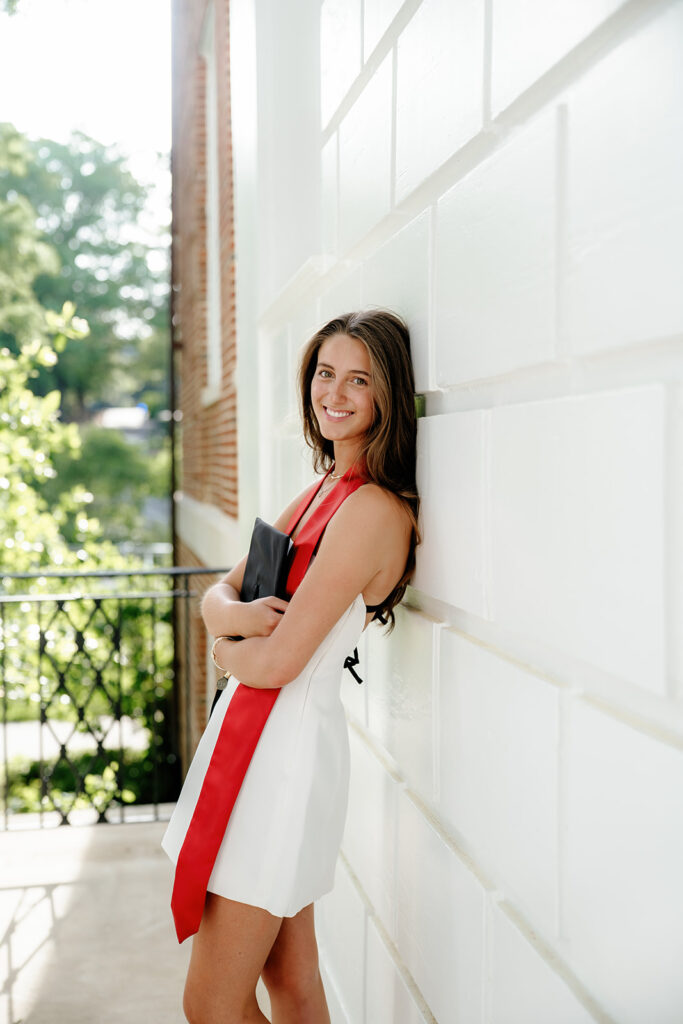 The University of Maryland Graduation Portrait at ESJ Building of graduate leaning against building holding graduation cap