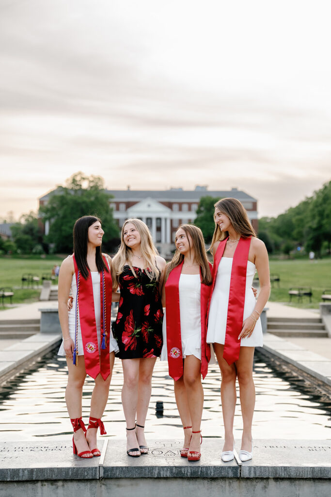 Best friends laughing and smiling while standing on the fountain ledge at the University of Maryland's McKeldin Mall