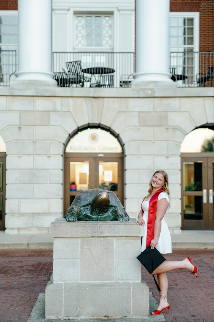Photo of graduate with Testudo Statue in front of McKeldin Library