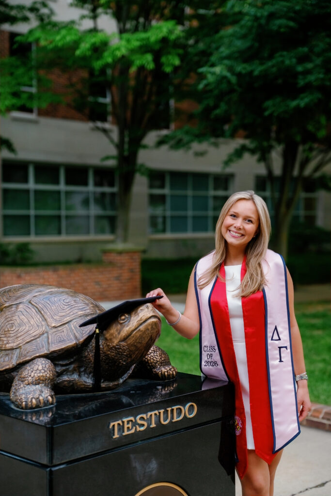 Photo of graduate with Testudo Statue in front of Van Munching