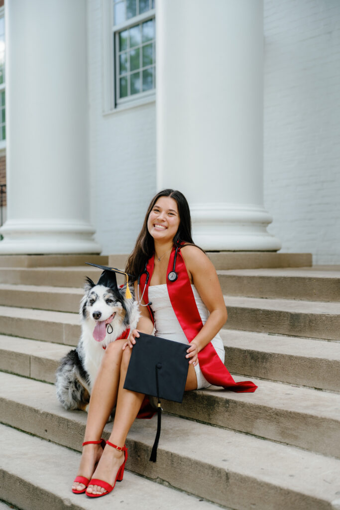 UMD Grad posing with her dog wearing a graduation cap at the university of Maryland posing for a photo on McKeldin Mall